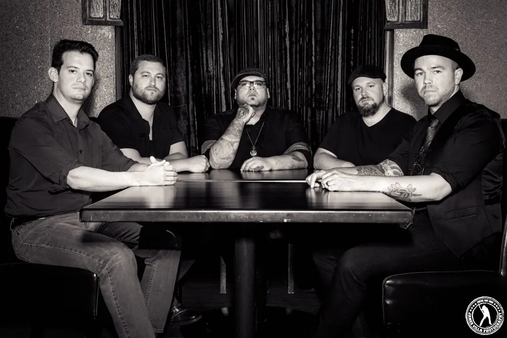 Heart of the City, five men in black around a dark table, in black and white.